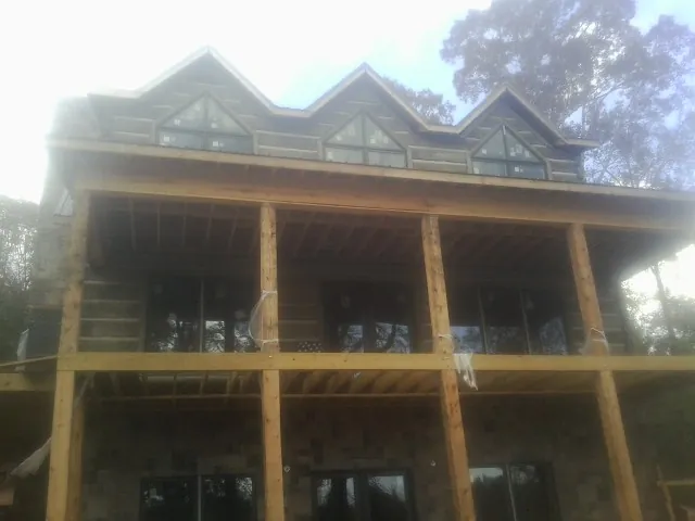 Dormers and porch framing on a large log home under construction — Roof Coating work by our crew in Bergholz
