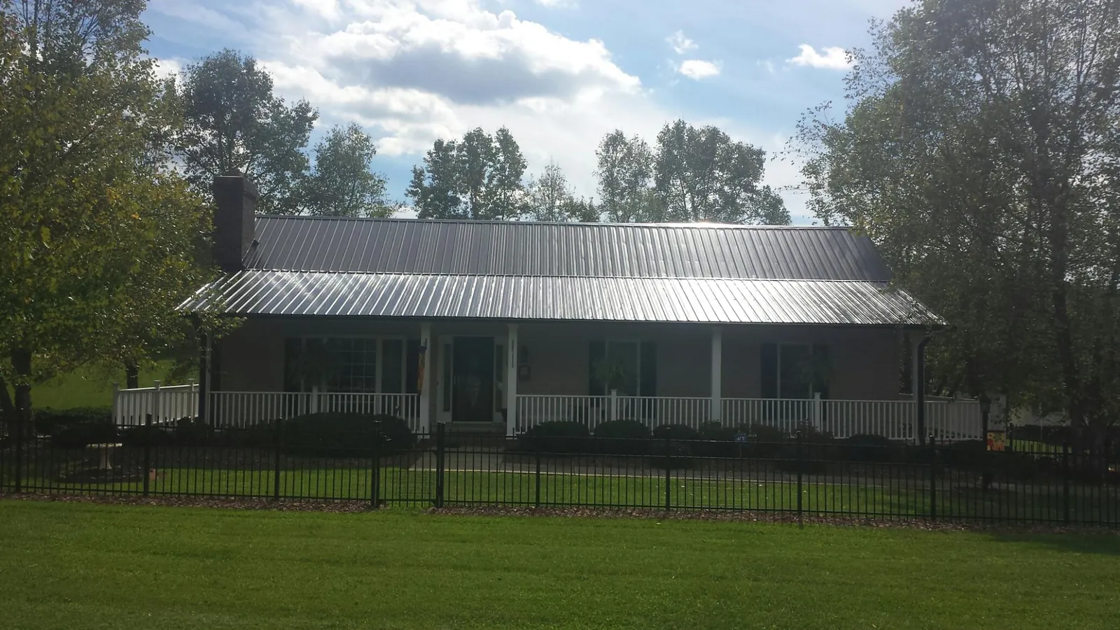 Gray metal roof on a brick ranch with a full width front porch — Gutter Guard Installation work by our crew in Bergholz