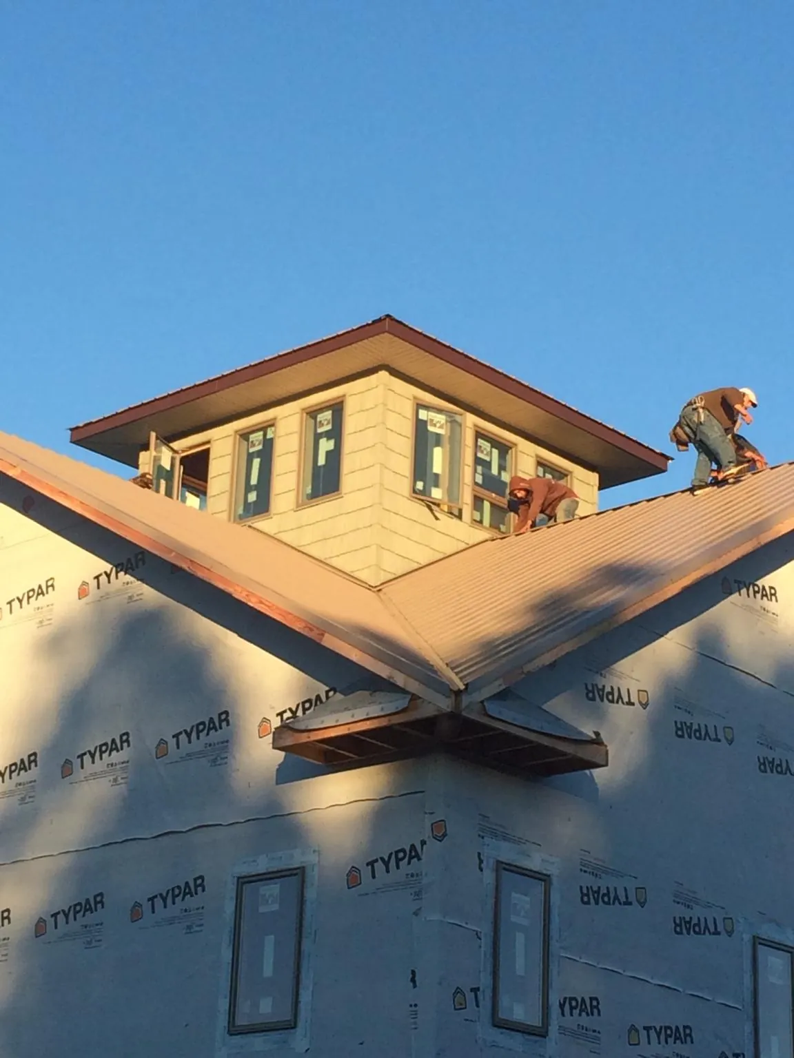 Roofers working around a rooftop cupola on a new metal roof at sunset — Roof Waterproofing in Bergholz by Roofing Brothers